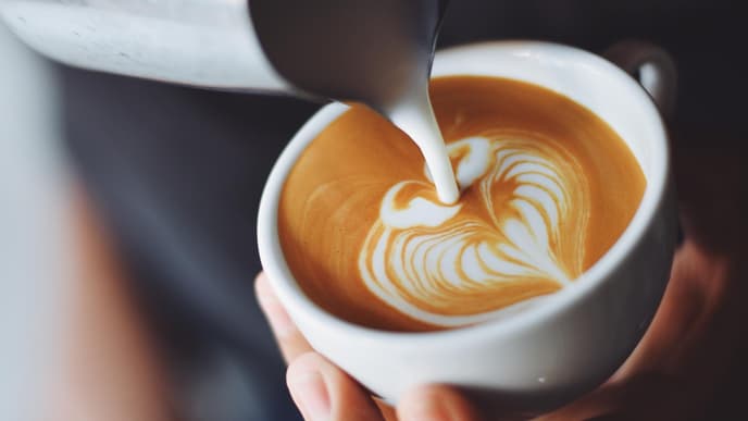 Milchschaum wird in Tasse gegossen