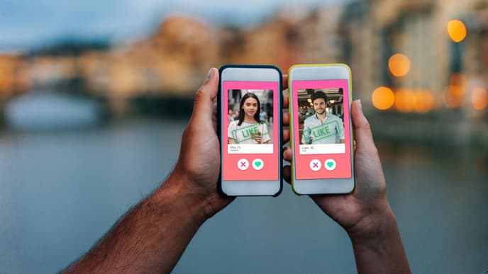 Hand von Mann und Frau mit Smartphone jeweils in der Hand, auf welchem Tinder geöffnet ist