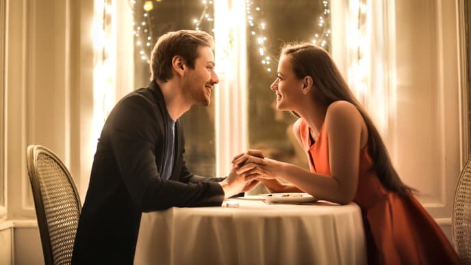 Valentinstag Date: Mann und Frau sitzen an einem Tisch der mit Lichterketten geschmückt ist