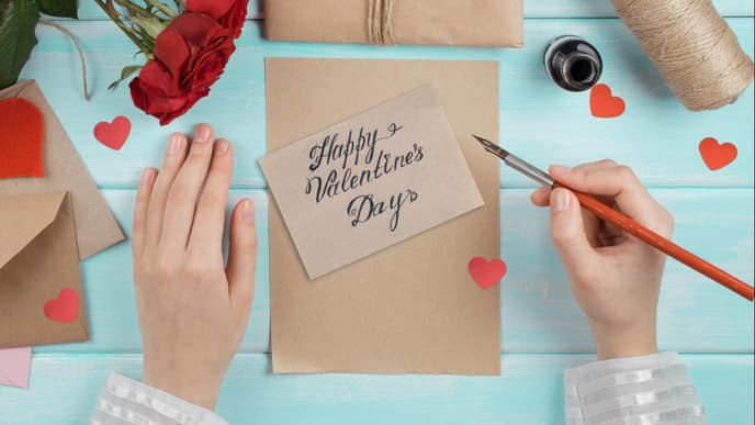 Valentinstag Sprüche: Zwei Hände schreiben eine Valentinstag Karte