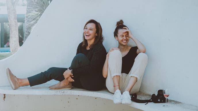 Zwei junge Frauen sitzen und lachen