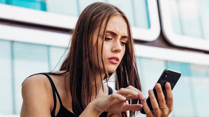 Frau schaut besorgt auf Handy
