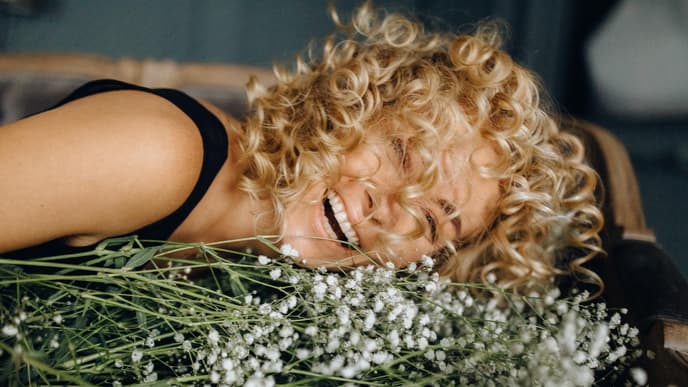 Horoskop: Frau lacht auf weißen Blumen
