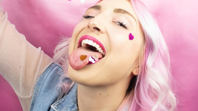 Horoskop: Frau mit rosa Haaren und Konfetti im Mund