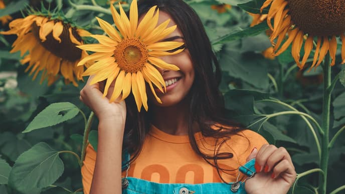 Horoskop: Frau mit Sonnenblume vor dem Gesicht