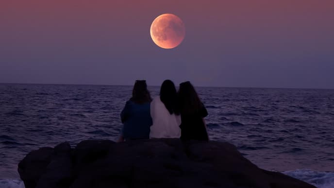 Drei Leute sitzen vor Supermond