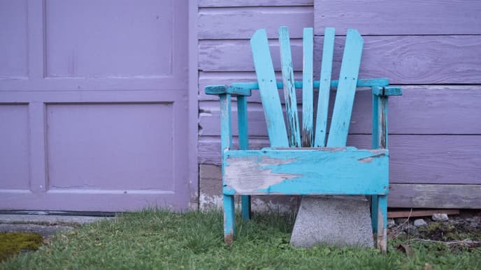 Gartenmöbel pflegen: Blauer Stuhl vor lila Wand