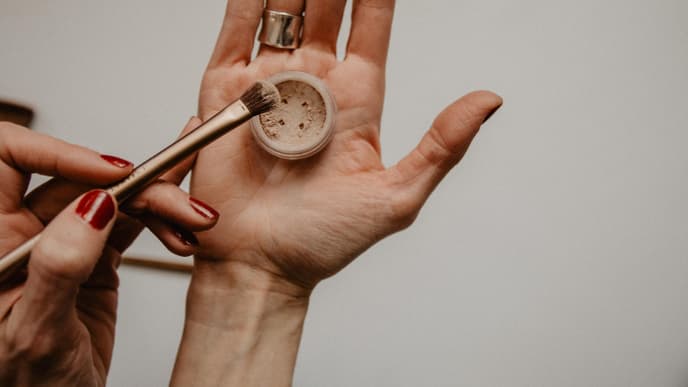 Hand hält Make up Puder und Pinsel