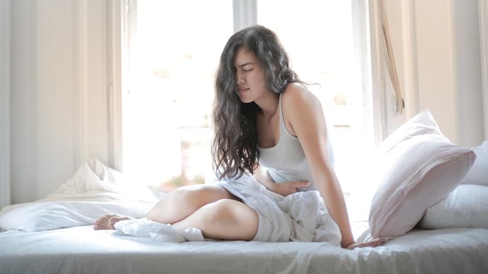 Frau mit Bauchschmerzen im Bett