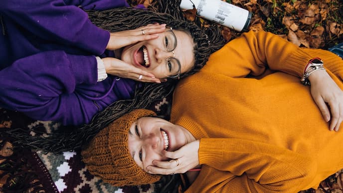 Zwei Frauen liegen nebeneinander und lachen