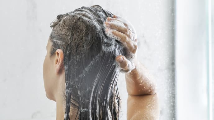 Frau wäscht sich die Haare mit Shampoo