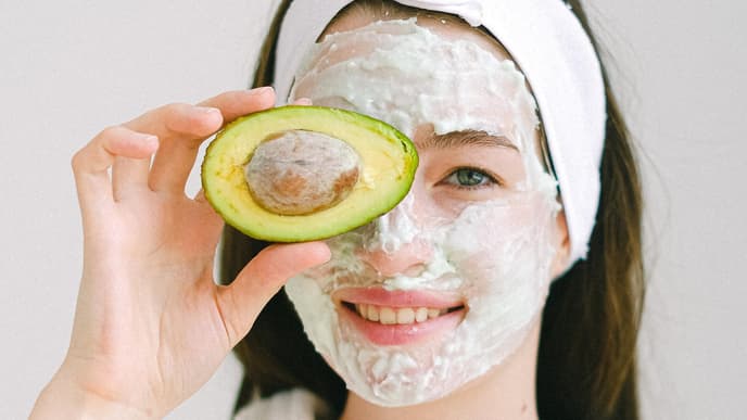 Frau mit Gesichtsmaske und Avocado