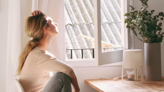 Frau schaut müde aus dem Fenster