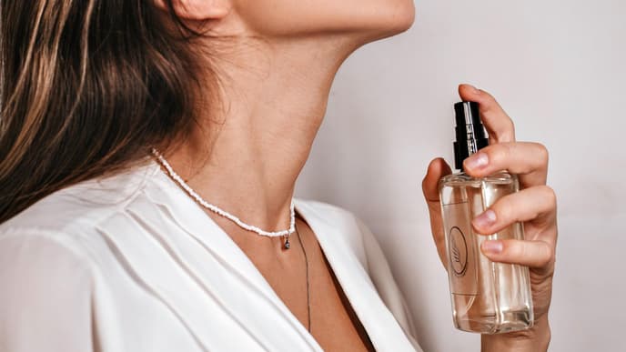 Frau sprüht Parfum auf