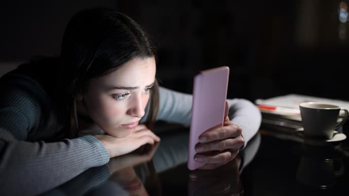 Frau guckt traurig auf ihr Smartphone