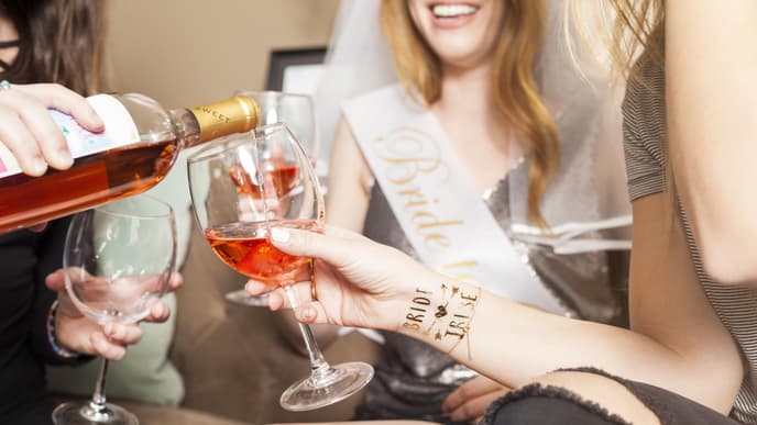Frauen feiern Junggesellinnenabschied und schenken der Braut und sich Alkohl ein 