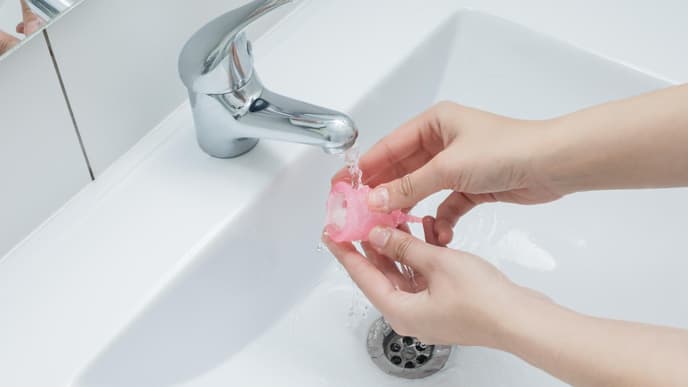 Menstruationstasse unter Wasserhahn reinigen