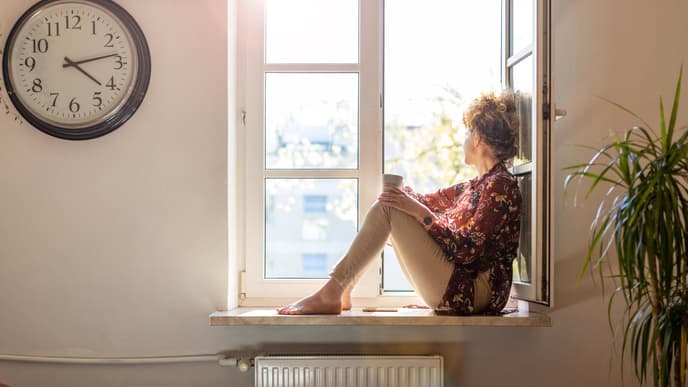 Frau sitzt alleine am Fenster