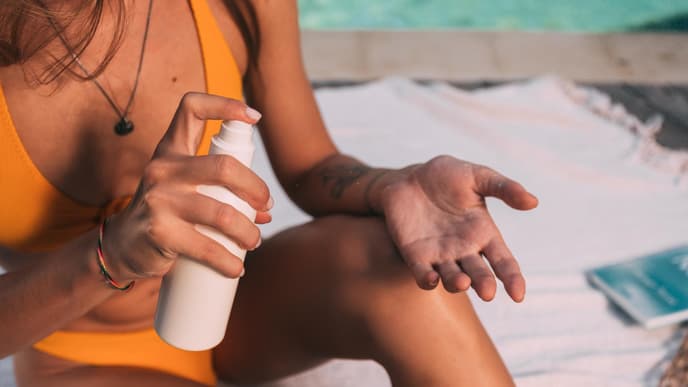 Frau cremt sich mit Sonnenmilch ein