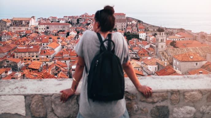 Frau mit Rucksack steht über Stadt