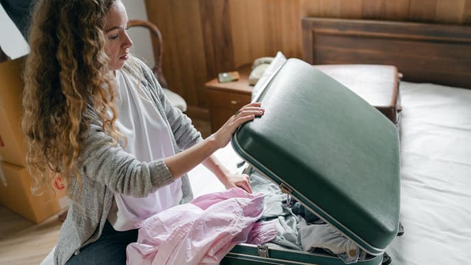 Frau packt Koffer auf dem Bett