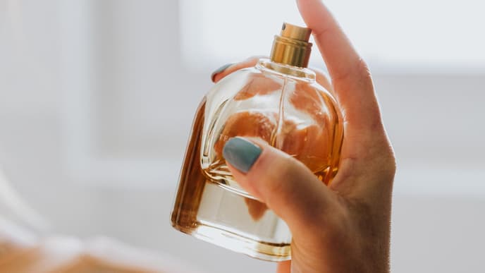 Frau hält Parfumflacon in der Hand