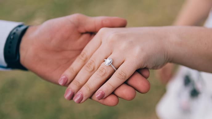 Mann hält Hand von einer Frau mit einem Verlobungsring