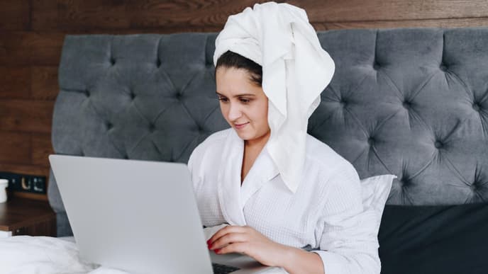 Frau in Bademantel am Laptop
