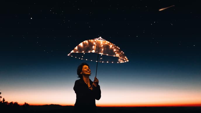 Frau mit Regenschirm vor Sternhimmel