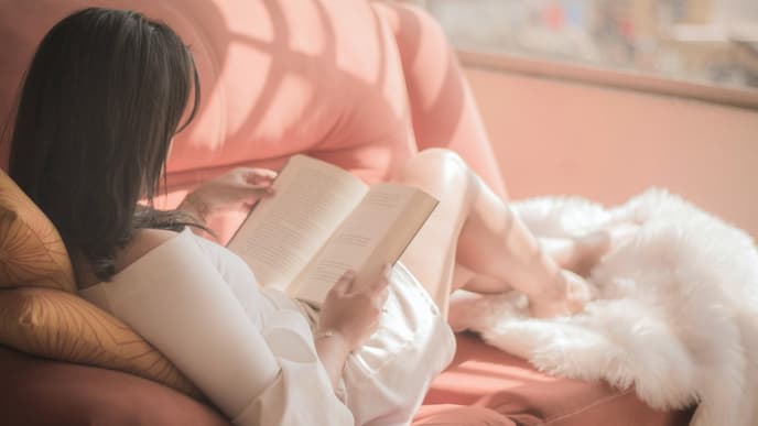 Frau liest Buch auf dem Sofa
