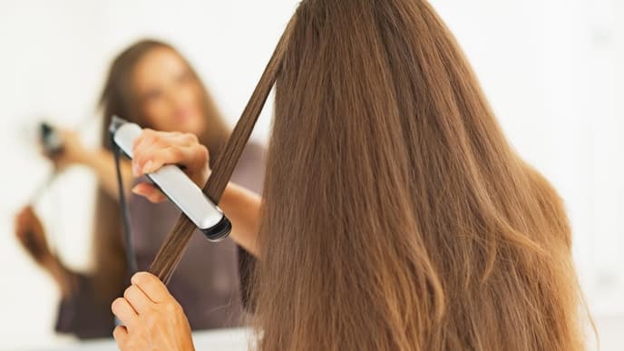 Frau glättet sich Haare