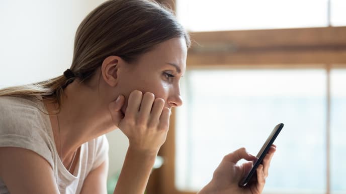 Frau schaut traurig auf Handy