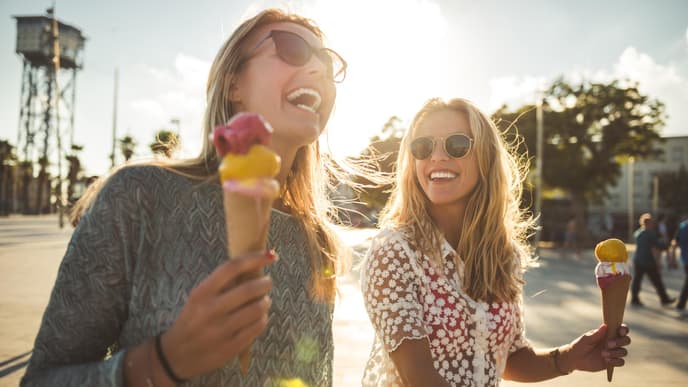 Zwei Freundinnen lachen und essen Eis