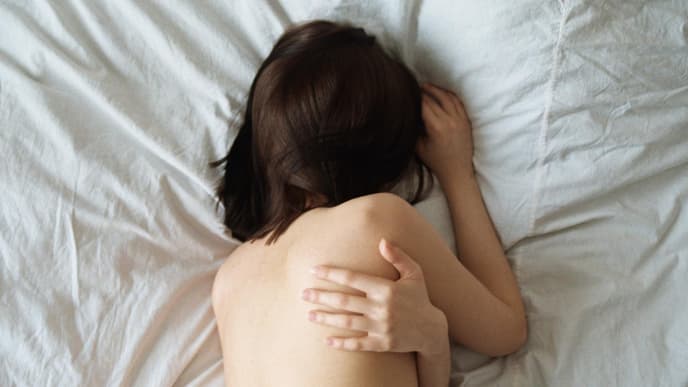Frau schläft nackt im Bett