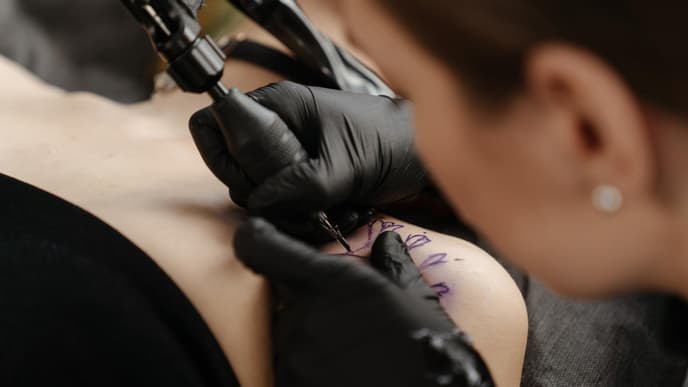 Frau lässt sich Tattoo stechen