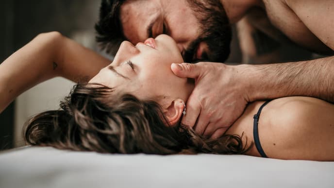 Mann küsst Hals der Frau im Bett
