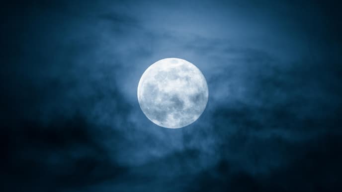 Der Vollmond steht am Himmel hinter Wolken