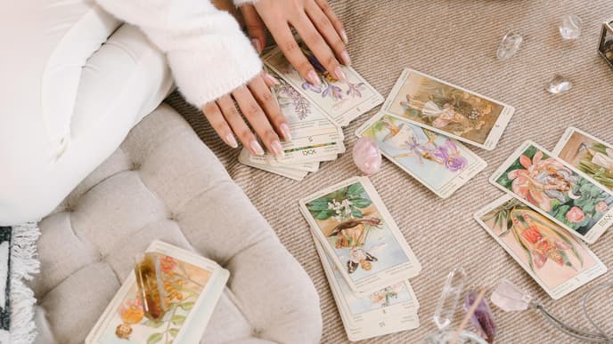 Frau hat vor sich Tarot-Karten und Kristalle liegen
