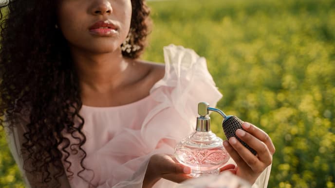 Frau hält rosa Parfum Flakon in der Hand