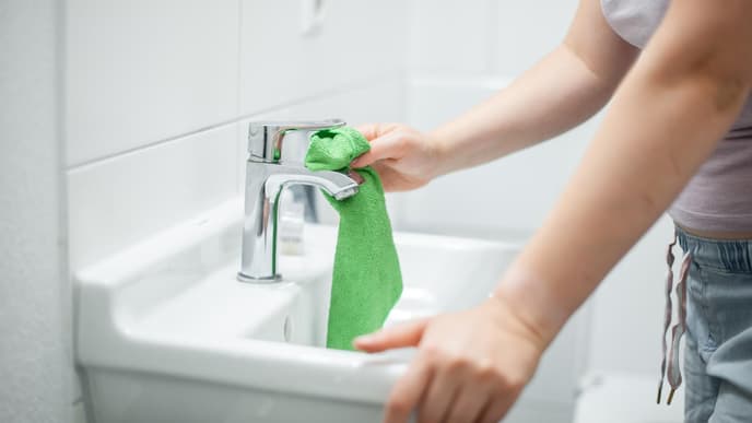 Frau putzt Waschbecken Badezimmer