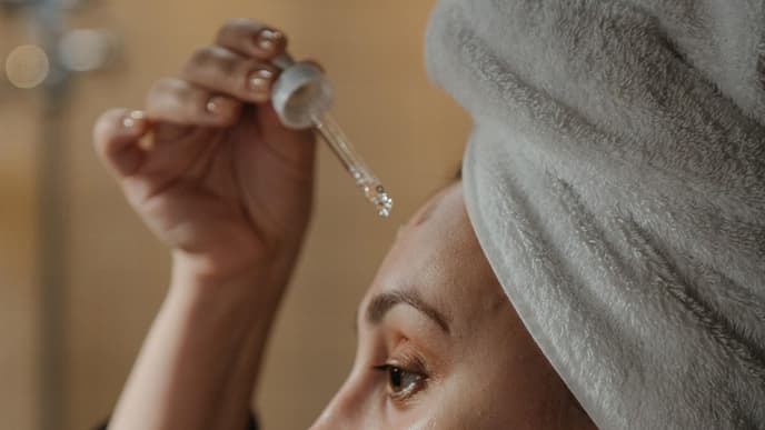 Frau trägt Hautpflege mit Pipette auf