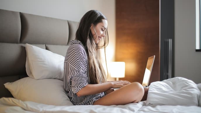 Junge Frau am Laptop im Bett