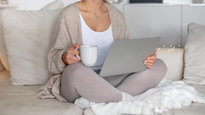 Frau sitzt in Thermowäsche Zuhause auf der Couch