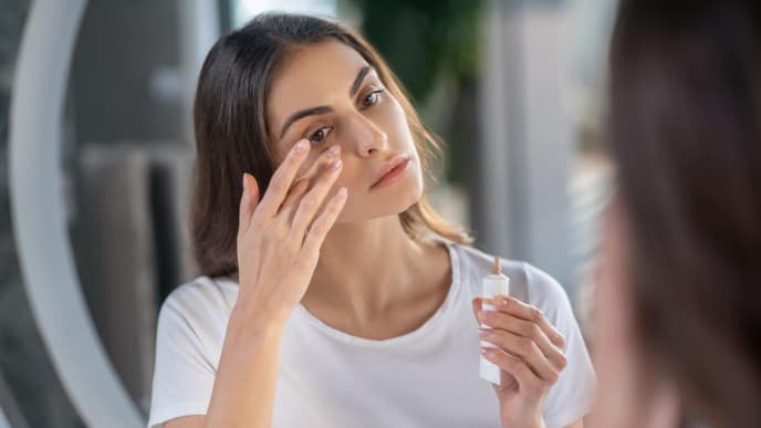 Frau deckt Augenringe mit Concealer ab