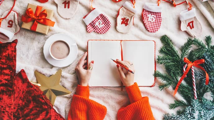 Person schreibt in weihnachtliches Buch