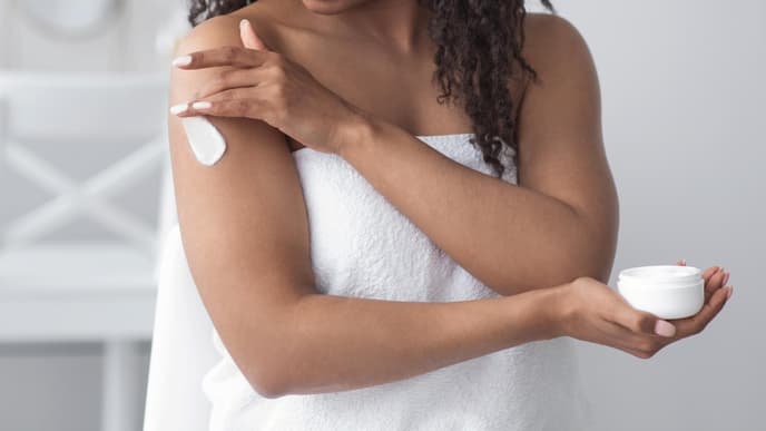 Frau trägt Bodylotion auf
