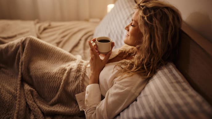 Junge Frau trink Tee im Bett 