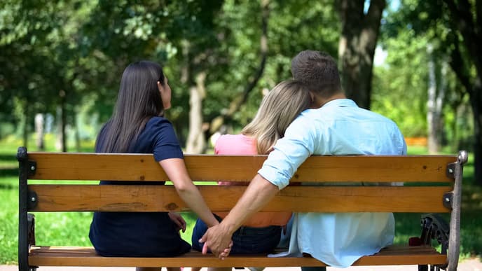 Mann hält Hand mit einer Frau hinter einer Bank