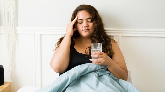 Frau im Bett fasst sich an den Kopf