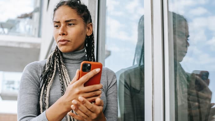 Frau hält ein Handy in der Hand und guckt traurig
